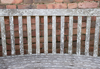 An old bench against a red brick wall