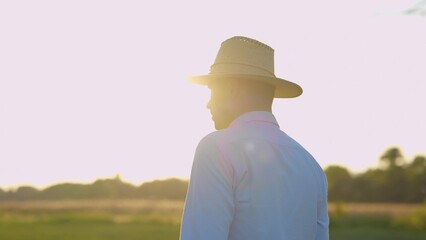 Close up portrait of handsome male in aht standing in countryside at sunset or sunrise and looking...