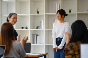 Smiling Asian student woman having presentation while her classmates giving applause