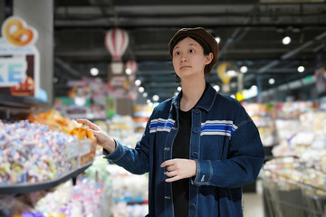 Young Shopper Choosing Products in Supermarket Aisle
