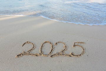 New Year 2025 handwritten in the white sand surface.