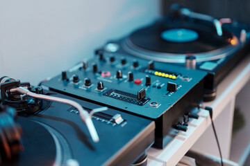 Close-up of a DJ turntable, mixer, and vinyl record for music entertainment.