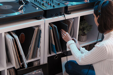 A person browsing through vinyl collection with turntable setup at home.