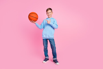 Obraz premium Full body photo of cool schoolboy indicate finger hand hold basketball empty space isolated on pink color background