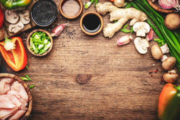 Food background, stir fry chicken cooking. Wooden table with vegetables, spices and ingredients for preparing Asian dishes with mushrooms and soy sauce. top view, copy space