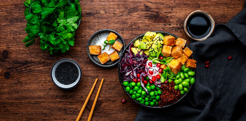 Vegan Buddha Bowl for balanced diet with tofu, quinoa, vegetables and legumes. Wooden table...