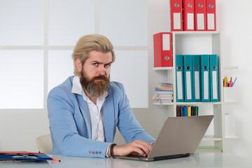 Serious Business man working with Stacks of paper files. Searching information. Report papers and piles of documents achieves on laptop computer desk in office. Male secretary working in office.