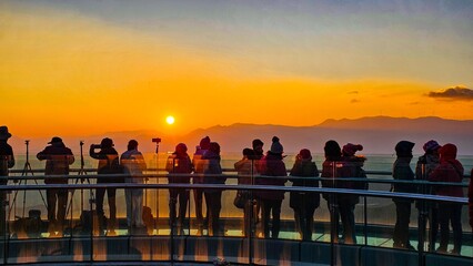 Group of people on glass walkway admire sunset in Damakan, Kunming City, Yunnan, China