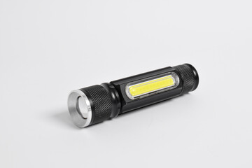 Modern metal LED flashlight in black color isolated on white background. Portable flashlight, LED...
