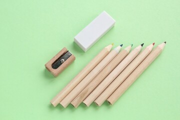 Colored pencils, wooden manual sharpener and eraser on green background. Back to school concept....