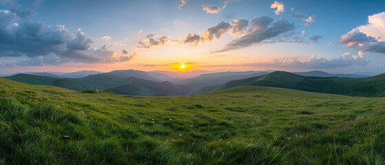 Beautiful nature summer scene with green grass on mountains hills and sunset cloudy sky over mountains as background looking at wide angle lens