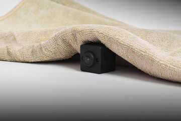 Closeup spy camera under cloth on white background. Black security camera, Mini spy camera