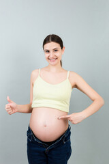 Young beautiful teenager girl pregnant expecting baby over isolated colored background smiling showing big belly