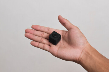 Hand holding a spy camera isolated on white background. Black security camera, Mini spy camera
