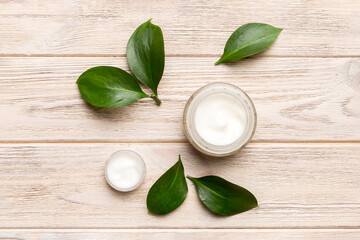 Organic cosmetic products with green leaves on wooden background. Flat lay