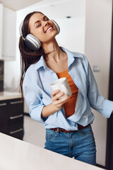 Young woman enjoying music and coffee in kitchen