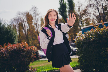 Photo of sweet friendly girl wear uniform walking school waving arm palm hi outside urban city park