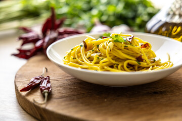 A plate of spaghetti aglio e olio with chili flakes, fresh parsley, garlic, and a drizzle of extra...
