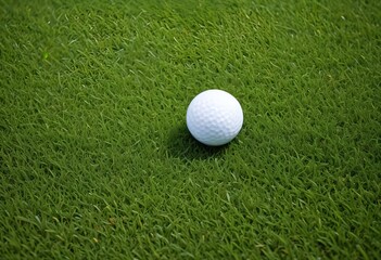A white golf ball resting on a lush green grass field