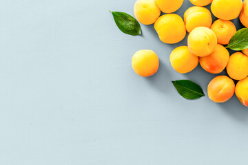Fruit background with apricots and leaves on blue background top view copy space
