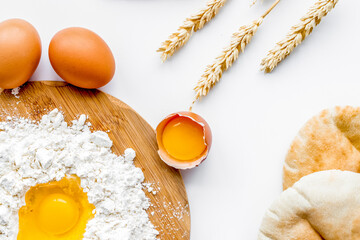 Make bread concept. Flat bread near wheat ears, flour and eggs on white background top view