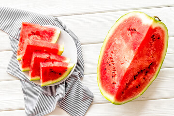 Cut watermelon for break with fruit on white wooden background top view