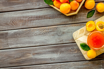 Summer preserves. Apricot jam in jar near fresh fruits on dark wooden background top view frame copy space