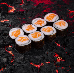 Creative concept of sushi rolls on a fiery lava textured background