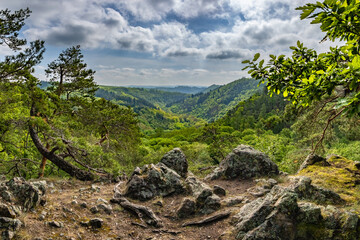 Rocky viewpoint over valley and surrounding spring forests under blue sky