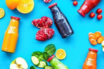 bottles with fresh carrot, tomato, apple, cucumber, lemon, pomegranate juices on blue background top view copyspace