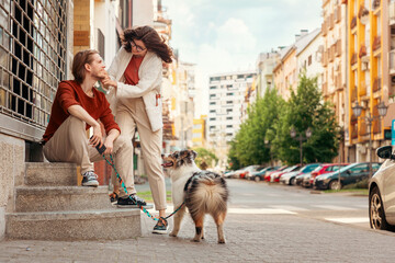 Happy young Caucasian married couple walks around city with purebred dog Aussie. Pet training