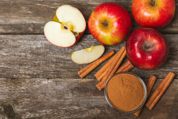 Apples with cinnamon on a textured wooden background. Fragrant red spiced apples with cinnamon sticks and star anise. Apple slices with spicy spices. Place for text. Copy space. Harvesting. Fruits. 