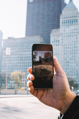 Cropped image of male taking picture of urban setting in downtown via application and camera on...