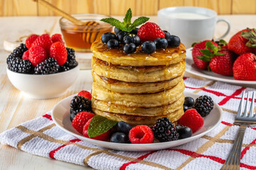 Delicious pancakes with fresh berries on white wooden table. Food concept.