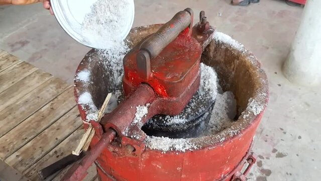 Footage of a man pouring salt into a machine to freeze ice cream. How to make Qalfa. Manual kulfa making machine in pakistan. Add salt. Beautiful 4K footage.