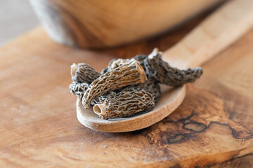 Dry Morel Mushrooms on Wooden Platter. Close-up of textured morel mushrooms, artfully arranged on a...