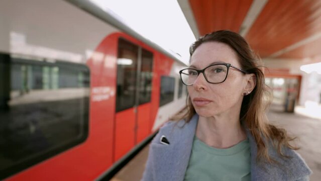 The portrait of a pretty middle-aged woman with glasses traveling on public transport reflects her relaxed elegance and confidence.