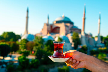 The Hagia Sophia Mosque. Man drinks black Turkish tea in front of the view. In the photo, the tea...