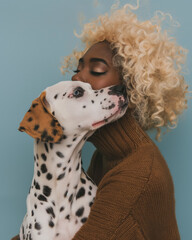 Elegant Affection: Portrait of fashion black woman and Dalmatian dog on blue background. Minimal animal concept with copy space.