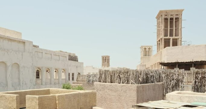 House in traditional Arabic architecture with wind tower. Traditional Arabic style building with windcatcher tower and palm leaves thatched roof. Old Dubai, UAE. View of rooftops of old Arab city