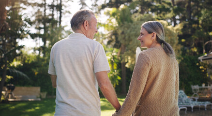 Mature, couple and walk with holding hands in garden for love or safety, support and care with compassion for romance. Senior man, woman and together in backyard with back view and relax outdoor.
