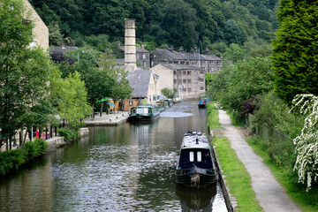 Boats in canal and old mill. Narrow boat on a British canal in rural setting. Hebden Bridge.