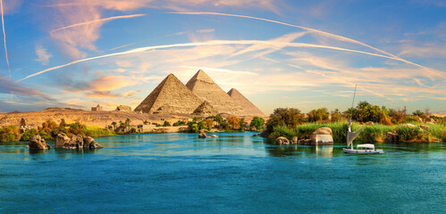 Lonely Saleboat in the Nile river and ancient rocks in the Aswan desert by the pyramids, Egypt