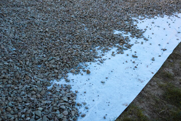 Geotextile layer between gravel. White Geotextile with gravel lies on a construction site. Modern construction technologies and materials. Country empty Road