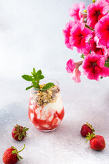 Healthy tasty breakfasts, glasses with muesli and yogurt, strawberry smoothies, pink petunias