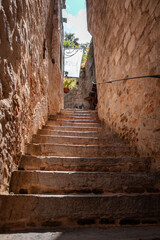 Bottom view of narrow cobbled steps leading up between walls of the old European city. Mediterranean historical sights and destination. Vertical orientation