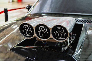 A car with a hood open and three exhaust pipes. The pipes are silver and have the number 8 on them