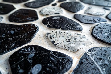 A detailed macro shot of wet black stone tiles with distinctive patterns and water droplets