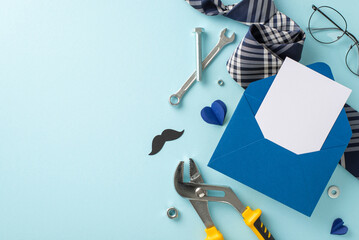 Stylish flat lay of a blue envelope, mustache cut-out, tools, and a striped tie on a pale blue...