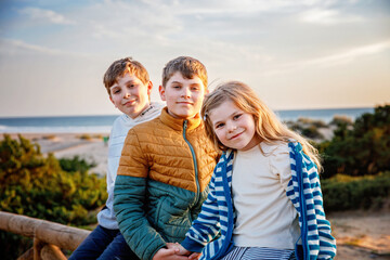 Portrait of three children, happy kids on beach at sunset. happy family, two school boys and one little preschool girl. Siblings having fun together. Bonding and family vacation